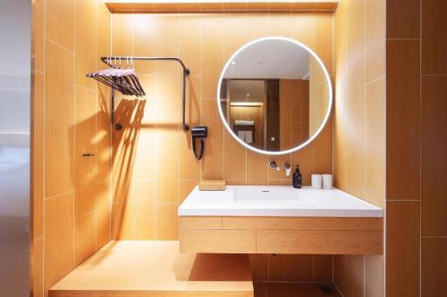 ein Bad mit einem Waschbecken und einem Spiegel in der Unterkunft Ji Hotel Harbin West Railway Station in Harbin