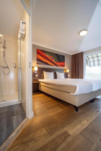 a bedroom with a large bed and a shower at Fletcher Hotel-Restaurant Arneville-Middelburg in Middelburg