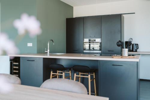 a kitchen with a counter with stools in it at Ridderstee Ouddorp Duin in Ouddorp