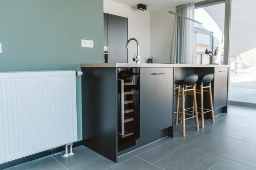 a kitchen with a sink and some bar stools at Ridderstee Ouddorp Duin in Ouddorp