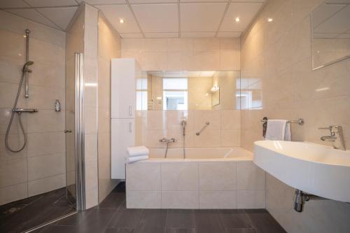 a bathroom with a tub and a sink and a shower at Fletcher Hotel-Restaurant Arneville-Middelburg in Middelburg
