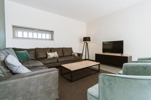 a living room with a couch and a tv at Ridderstee Ouddorp Duin in Ouddorp