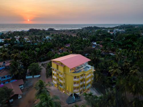 een uitzicht op een geel gebouw met uitzicht op de oceaan bij Bedzzz Xclusiv Morjim, Goa By Leisure Hotels in Morjim