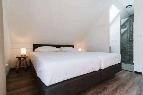 a bedroom with a large white bed and a window at Ridderstee Ouddorp Duin in Ouddorp