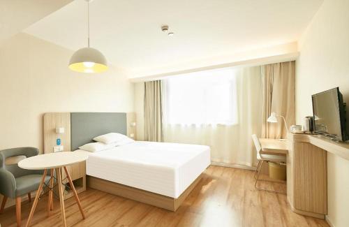 a bedroom with a white bed and a desk and a table at Hanting Hotel Guiyang Huaguoyuan Twin Towers in Sanqiao