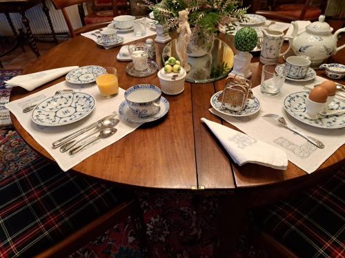 a wooden table with plates and utensils on it at Le Logis Fleurs et jardins de Pitry in Thierville