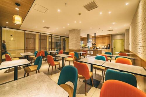 un restaurant avec des tables et des chaises et une cuisine dans l'établissement Hanting Hotel Qingdao Zhanqiao Railway Station East Plaza, à Qingdao