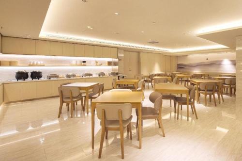 a restaurant with tables and chairs and a kitchen at Ji Hotel Dalian Railway Station in Dalian