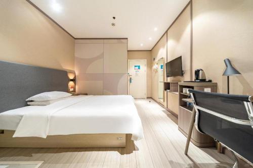 a bedroom with a large white bed and a television at Hanting Hotel Shanghai Qingpu Caoying Road Metro Station in Qingpu