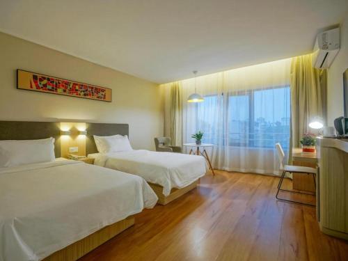 a hotel room with two beds and a large window at Hanting Hotel Nanjing Hexi Jiqingmen Street in Nanjing