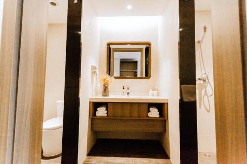 a bathroom with a sink and a toilet and a mirror at Hanting Hotel Wenzhou Leqing Liushi Town in Hengdaiqiao