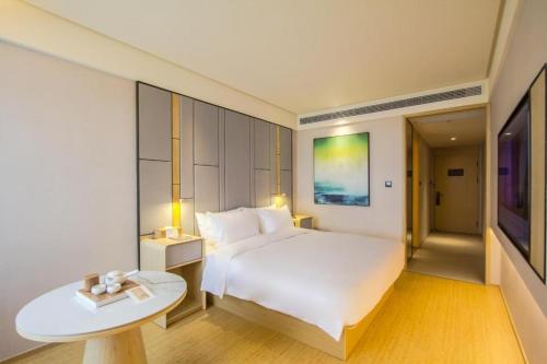 Un dormitorio con una gran cama blanca y una mesa en Ji Hotel Hangzhou Linping Xincheng, en Yuhang