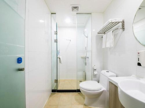 a white bathroom with a toilet and a shower at Hanting Hotel Zhengzhou Technology Market in Zhengzhou