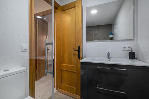 a bathroom with a sink and a wooden door at Jade Central Apto & Two Patios in Córdoba