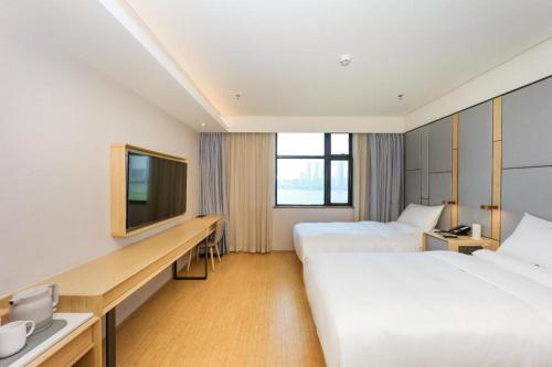 a hotel room with two beds and a television at Ji Hotel Nanchang Tengwang Pavilion in Nanchang