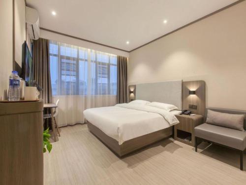 una camera d'albergo con letto e sedia di Hanting Hotel Zhijiang Yanjiang Avenue a Zhijiang