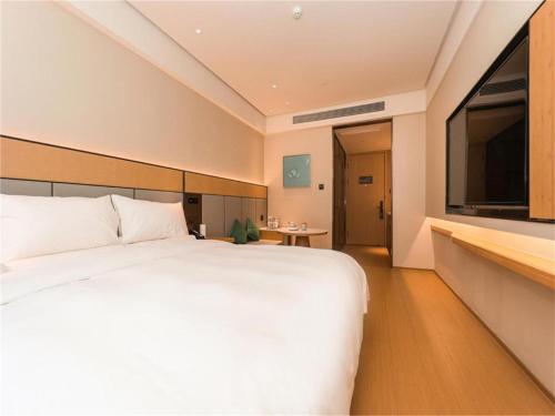 Ji Hotel Nanjing Baijia Lake في Jiangning: غرفة نوم بسرير ابيض ونافذة كبيرة