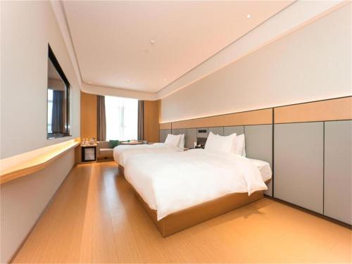 Ji Hotel Nanjing Baijia Lake في Jiangning: غرفة نوم بسرير ابيض كبير ونافذة كبيرة