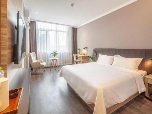 a bedroom with a large white bed and a table at Hanting Premium Hotel Qingdao Ocean University of China in Kutao