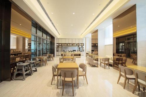 een restaurant met tafels en stoelen in een kamer bij Ji Hotel Jilin Wanda Plaza in Jilin