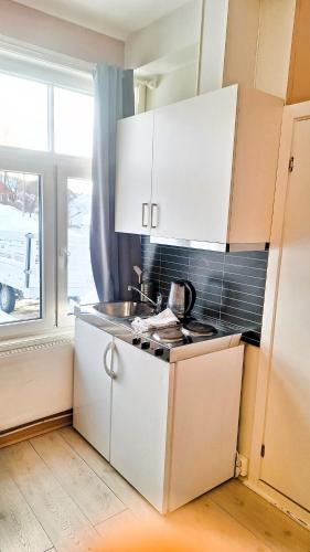 cocina con armarios blancos, fregadero y ventana en Sentrumsnær leilighet - K1 en Lillehammer