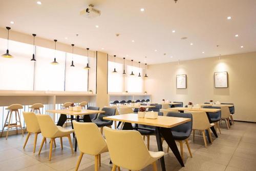 een restaurant met tafels, stoelen en ramen bij Hanting Hotel Nanyang Railway Station in Nanyang