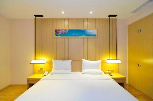 a bedroom with a large white bed with two lamps at Starway Hotel Guiyang Big Cross in Guiyang