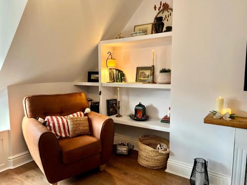 a brown chair in a room with shelves at Top floor 1BR apartment central Matlock in Matlock