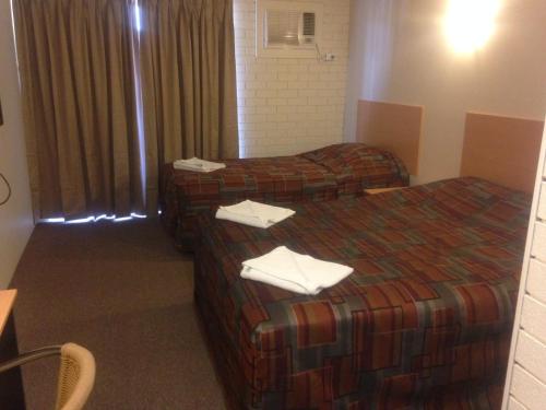 two beds in a hotel room with towels on them at Budget Motel in Midland Junction