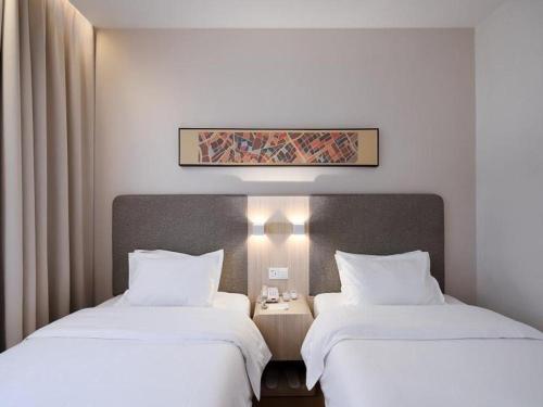 two beds sitting next to each other in a room at Hanting Hotel Nanjing Yaohuamen in Qianjiadu