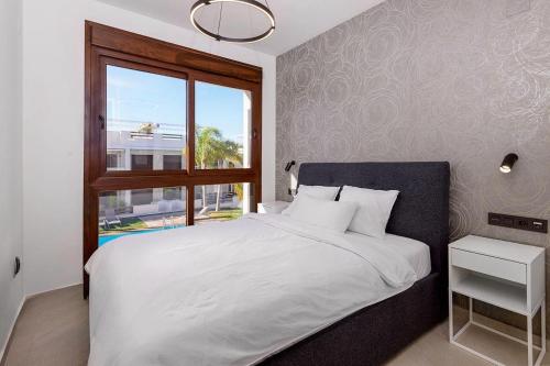 een slaapkamer met een wit bed en een raam bij Apartment Los Balcones - Torrevieja in Torrevieja