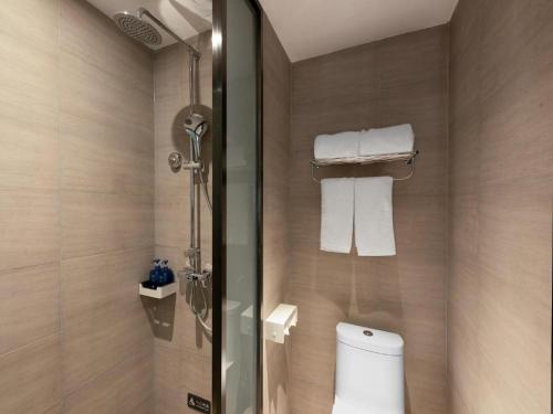 a bathroom with a toilet and a shower with towels at Hanting Hotel Xi'An Zhouzhi Water Street in Zhouzhi