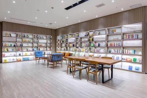 a library with a table and chairs and bookshelves at Hanting Hotel Taicang Wanda Plaza in Taicang