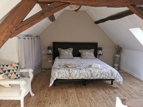 a bedroom with a bed and a chair in a attic at Gîte L'Escale Charmante in Choussy