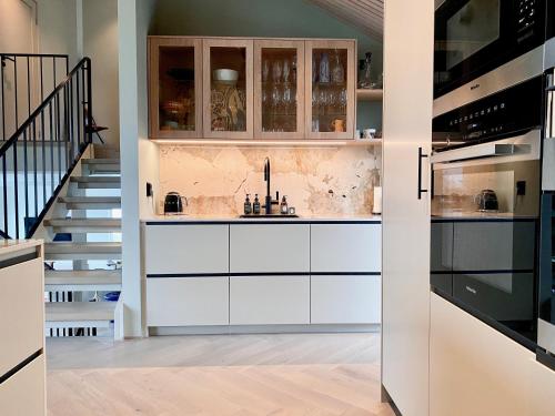 una cocina con armarios blancos y una escalera en Villa Bluebird en Henningsvær