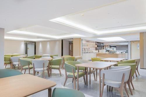 a dining room with tables and chairs and a kitchen at Ji Hotel Tianjin Cultural Center in Yutai