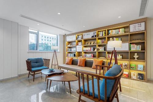a living room with a couch and a book shelf at Hanting Premium Hotel Yantai Development Zone Golden Beach in Fushan