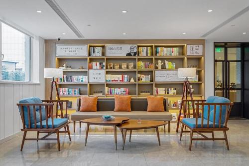 ein Wohnzimmer mit einem Sofa, Stühlen und Bücherregalen in der Unterkunft Hanting Premium Hotel Yantai Development Zone Golden Beach in Fushan