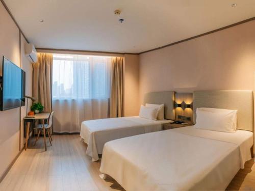 a hotel room with two beds and a television at Hanting Hotel Taiyuan Qianfeng South Road in Xiayuan