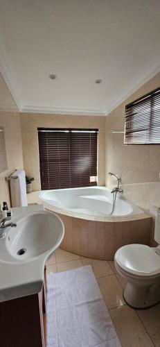 a bathroom with a tub and a toilet and a sink at Luxe Florida Grand Hotel in Durban