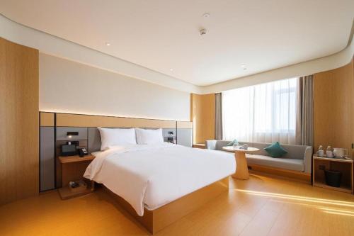 1 dormitorio con 1 cama blanca grande y 1 sofá en Ji Hotel Linfen Gulou South Street, en Linfen