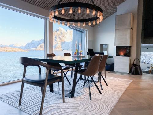 uma sala de jantar com mesa e cadeiras e uma grande janela em Villa Bluebird em Henningsvær