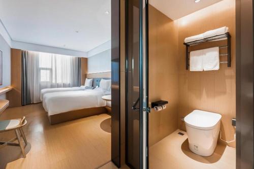 a hotel room with a toilet and a bed at Ji Hotel Fuzhou Wuyi Square in Fuzhou