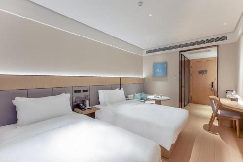 a hotel room with two beds and a desk at Ji Hotel Wenzhou Feixia South Road in Wenzhou