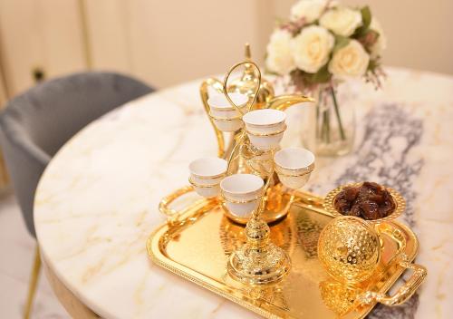 a gold tray with cups and glasses on a table at الدانة للشقق الفندقية in Kuwait