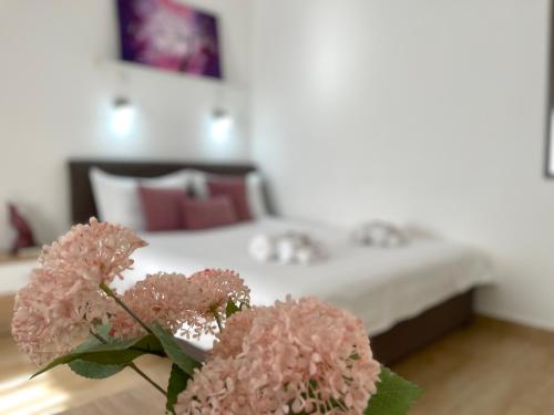a bedroom with a bed with pink flowers on a table at Apartments Pribilovic in Budva