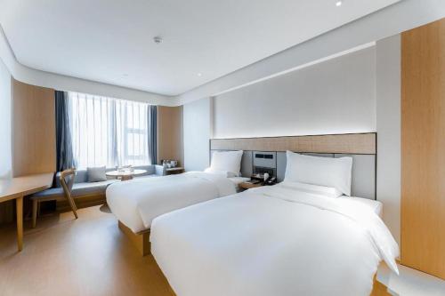 een hotelkamer met 2 bedden en een bureau bij Ji Hotel Guiyang Guanshan Lake High-Tech Zone in Jinzhuzhen