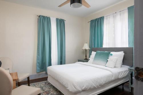 a bedroom with a large white bed with blue curtains at East Lake Stunner-Located at the foot of the Ruffner Mountains in Birmingham