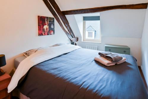 una camera da letto con un letto con una coperta blu e una finestra di Le duplex de Lise a Honfleur