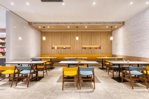 Hanting Premium Hotel Hangzhou West Lake Culture Square Metro Station في هانغتشو: غرفة طعام مع طاولات وكراسي صفراء